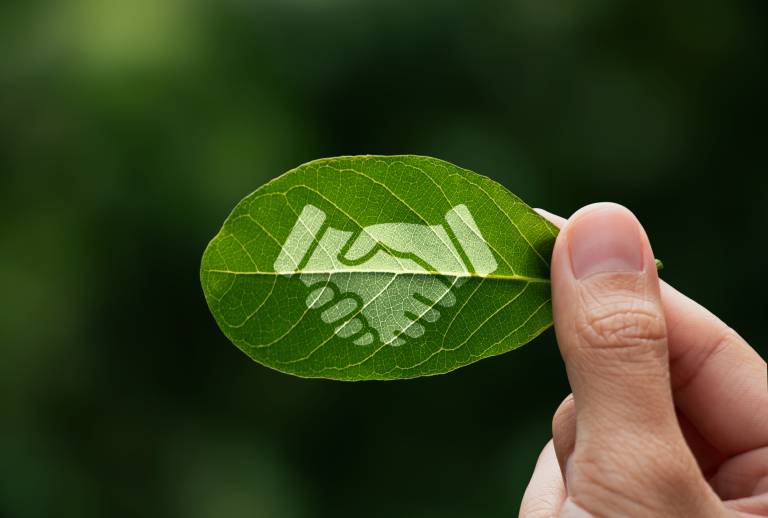 Hand of human is holding painted green leaf with handshake icon, environment social and governance or ESG, Cooperation of organization for prevent climate change sustainable earth.