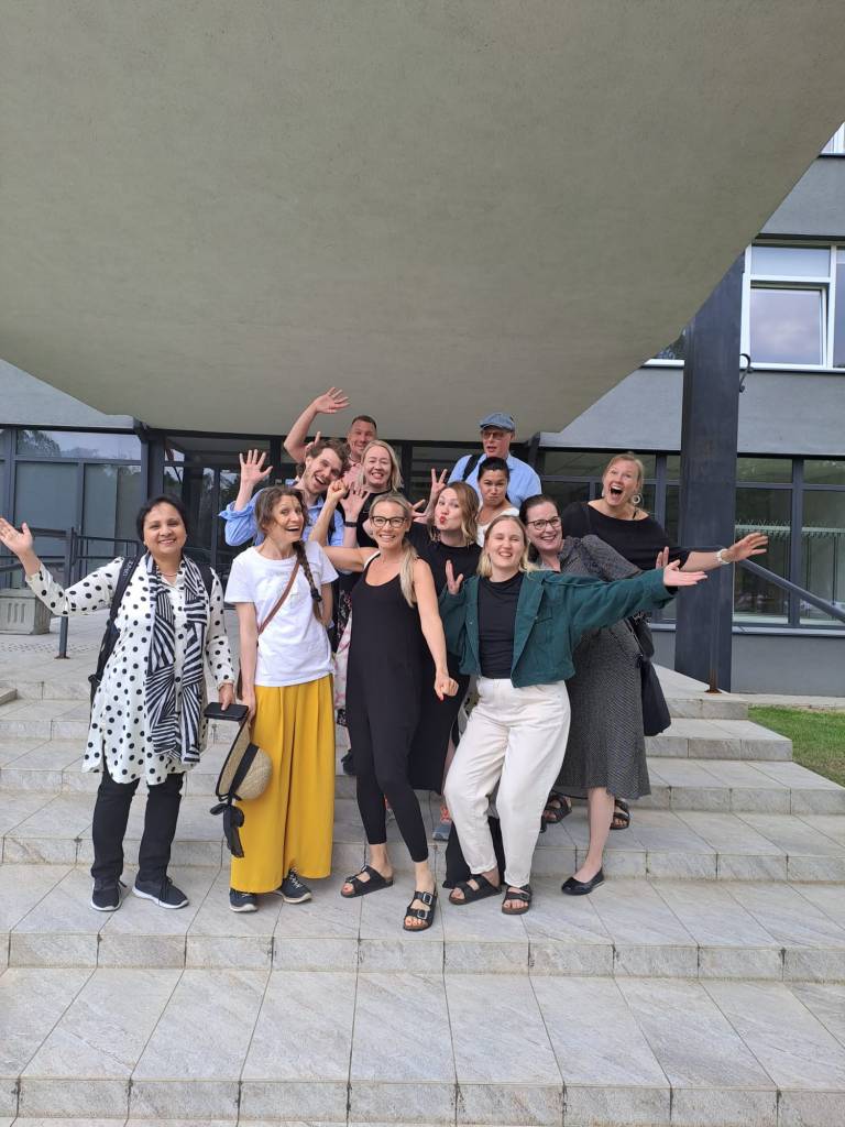 Ihmisiä seisomassa rappusilla ja vilkuttamassa kohti kameraa.