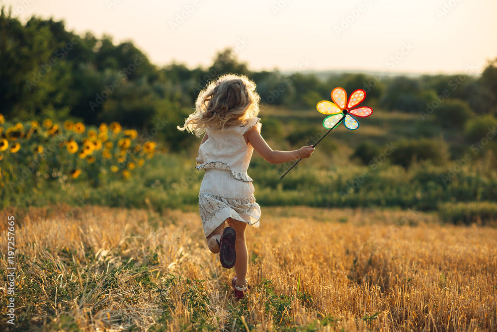 Pieni tyttö, joka juoksee pellolla.