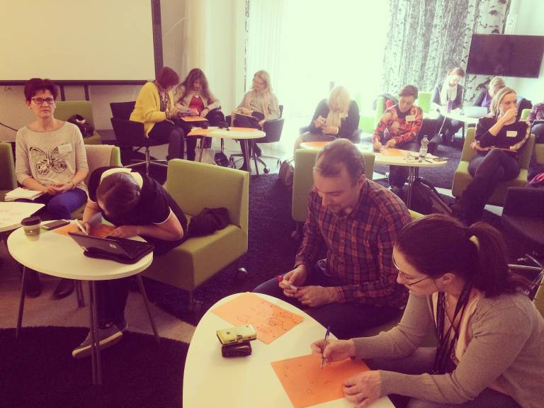 People writing on paper in classroom.