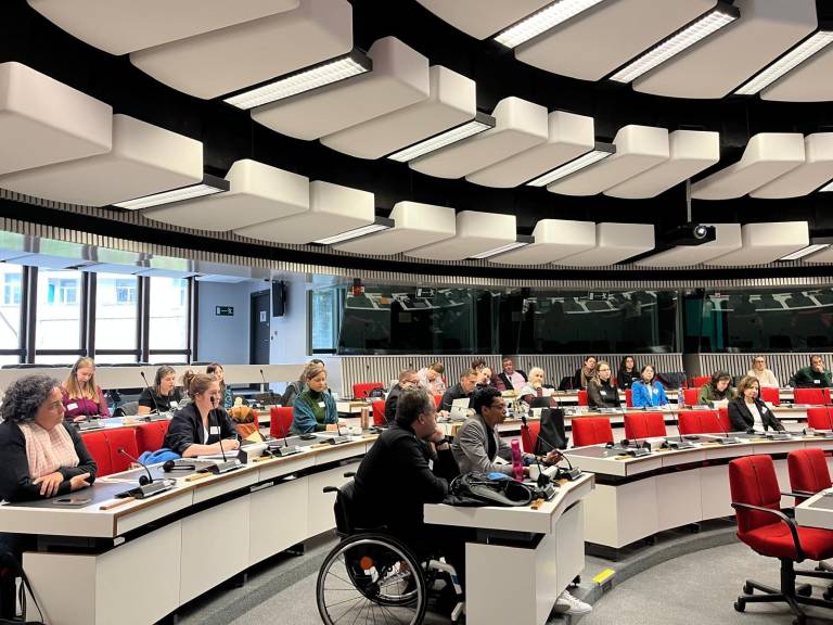 Ihmsiä istumassa suuressa seminaarissa pöytien ääressä.