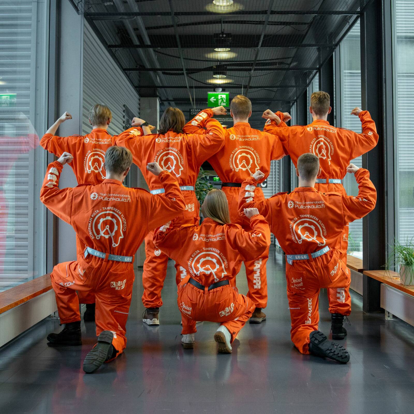 Opiskelijoita poseeraa oransseissa haalareissa.