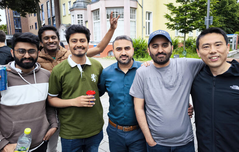 Group of men smiling outside.