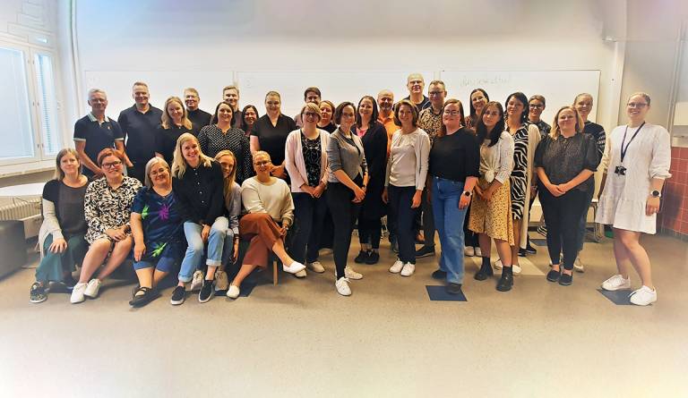 Iso joukko ihmisiä yhteiskuvassa luokkatilassa.