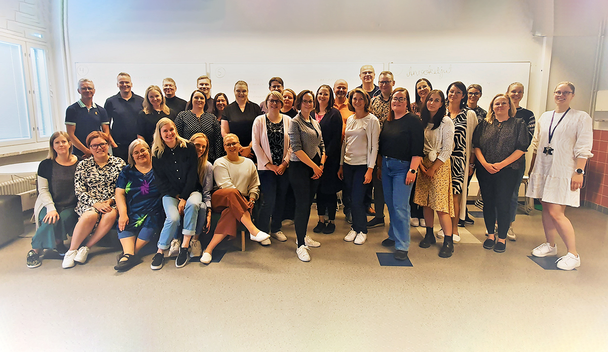 Iso joukko ihmisiä yhteiskuvassa luokkatilassa.