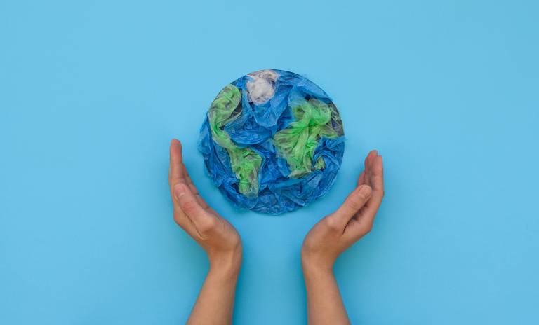 Kädet kohottautuvat kohti muovista puristettua maapalloa.