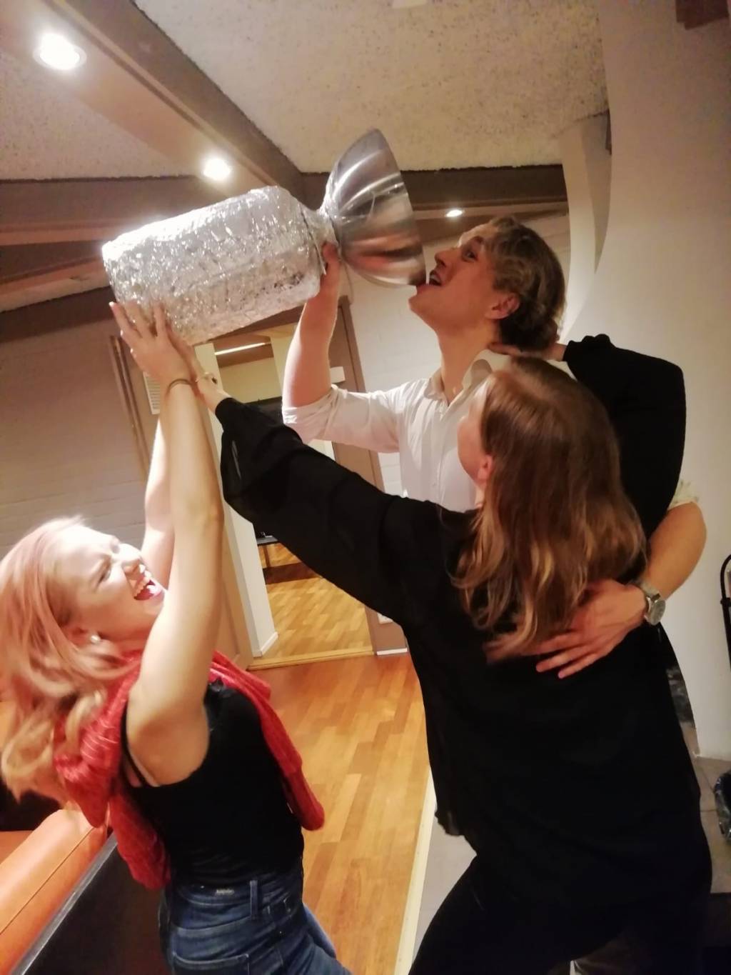 Voittajatiimin kolme jäsentä kallistaa voittomaljaa.