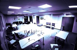 Kuva, jossa avoin luokkatila, istuimia ja työskentelypöytiä