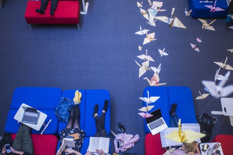 TAMKin kirjasto ylhäältäpäin, kuvassa näkyy opiskelijoita penkeillä sekä katosta roikkuvat origamit.