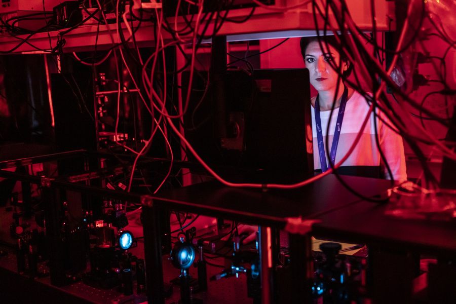 Opiskelija istumassa pöydällä näytön ja erilaisten johtojen kanssa.