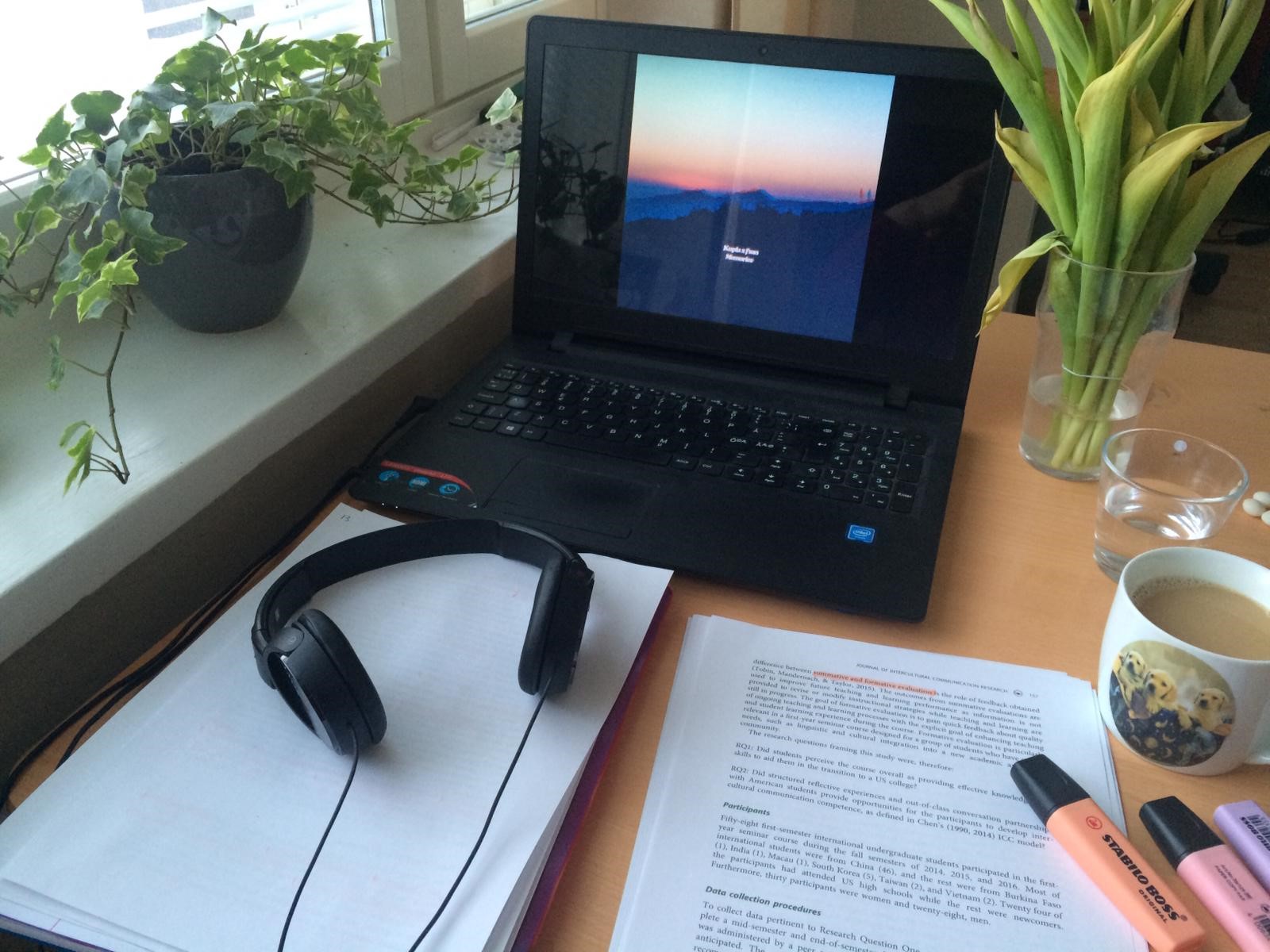 Läppäri, papereita ja kahvikuppi.