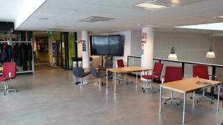 Lukion aulatila, jossa pöytiä ja tuoleja sekä älytaulu