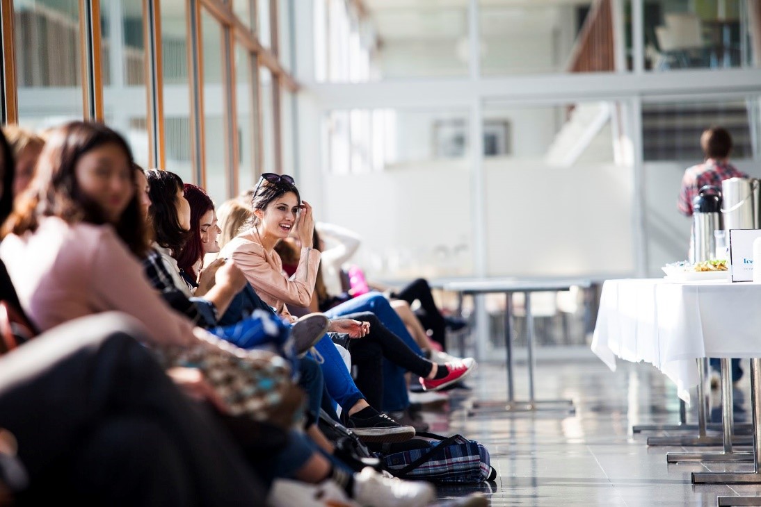 Opiskelijoita istumassa aulan penkeillä.