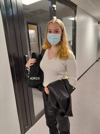 Kuva, jossa tyttö pitää kädessään Norssi-vilttiä eli mustaa vilttiä, jossa lukee Norssi