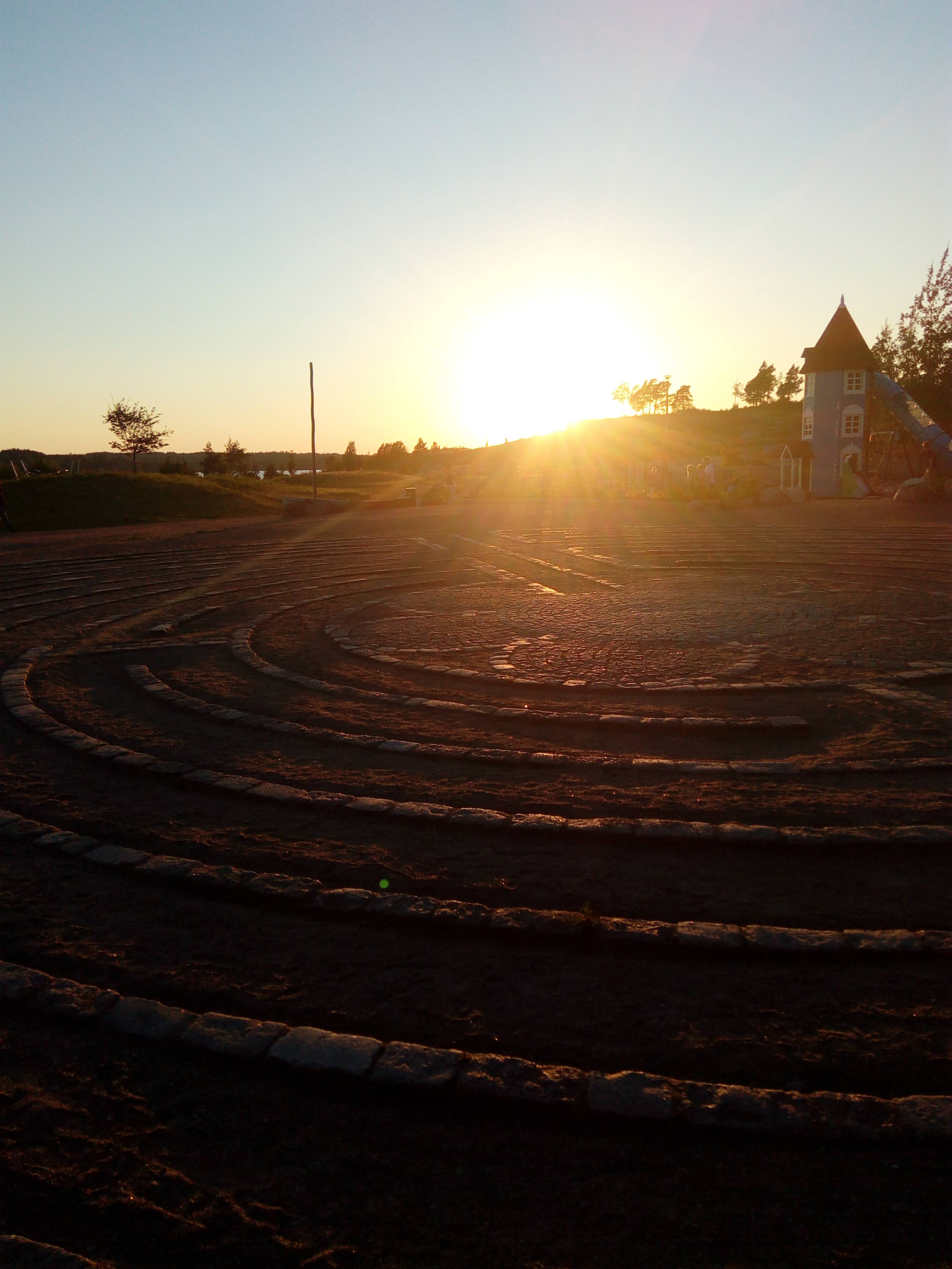 Maassa kivistä rakennettuja rengaskuvioita, taustalla auringonlasku.