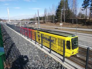 Keltaisessa ja punaisessa värityksessä oleva testiratikka kuvattuna yläviistosta Tampereen Turtolan ratikkapysäkillä keväällä 2020.