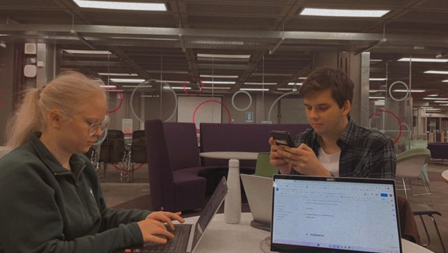 kaksi opiskelijaa, 3 tietokonetta ja puhelin