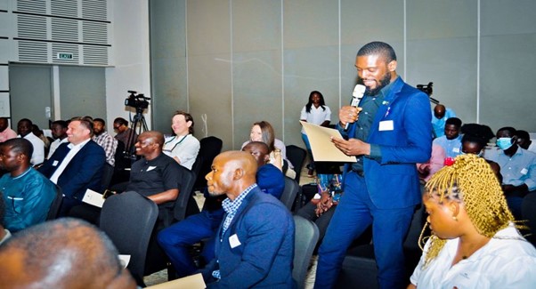 A man talking to the microphone while other participants listen.