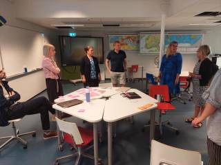 Kuva, jossa henkilöitä on kokoontunut yhteisen pöydän ääreen.