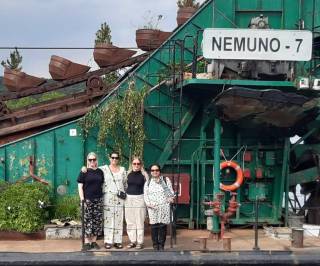 Neljä henkilöä seisoo ulkotaideteoksen edessä vierekkäin.