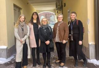 Viisi ihmistä seisovat vierekkäin.