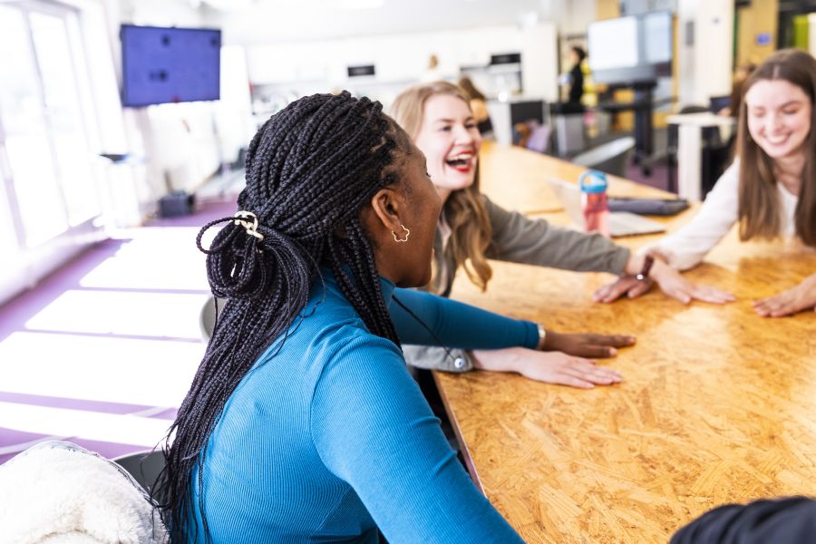 Opiskelijoita pöydän ääressä nauramassa.