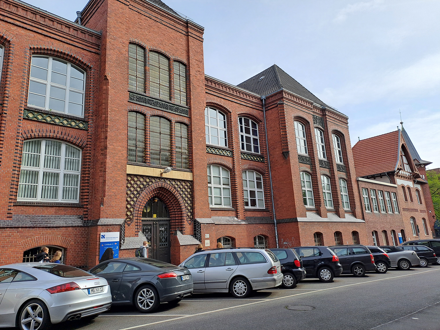 The oldest building of the Niederrhein University of Applied Sciences with cars parked in front of it.