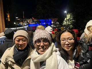 Three friends taking selfie against the blue lighted Tammerkoski dam in the background.