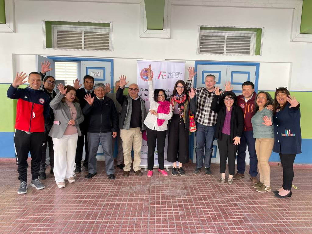 People in a group waving to the camera.