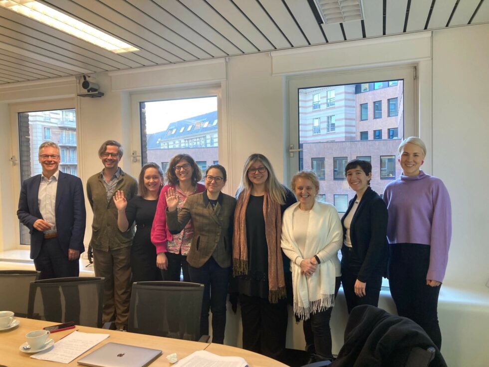 Ryhmä ihmisiä seisomassa ikkunoita vasten.