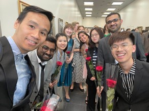 Students at their graduation ceremony in Tampere University. They are holding roses and smiling to the camera.