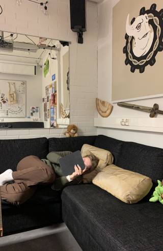 Opiskelija makaa sohvalla ja selailee Ipadia