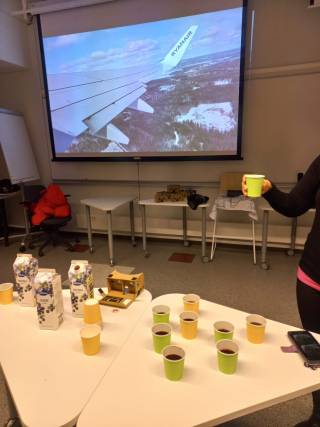 Virtuaalimatkalla. Kuvassa näkyy valkokankaallalentokoneen siipi ja osallistujan käsi.