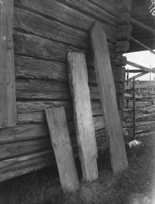 Vanha valokuva ruumislaudoista talon seinää vasten.