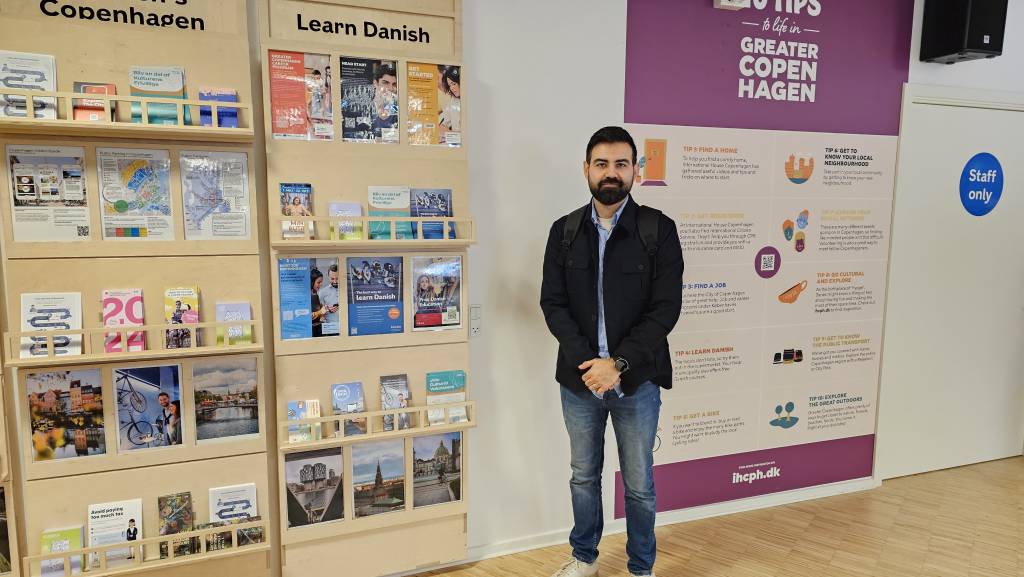 A man standing next to a wall full of brochures.
