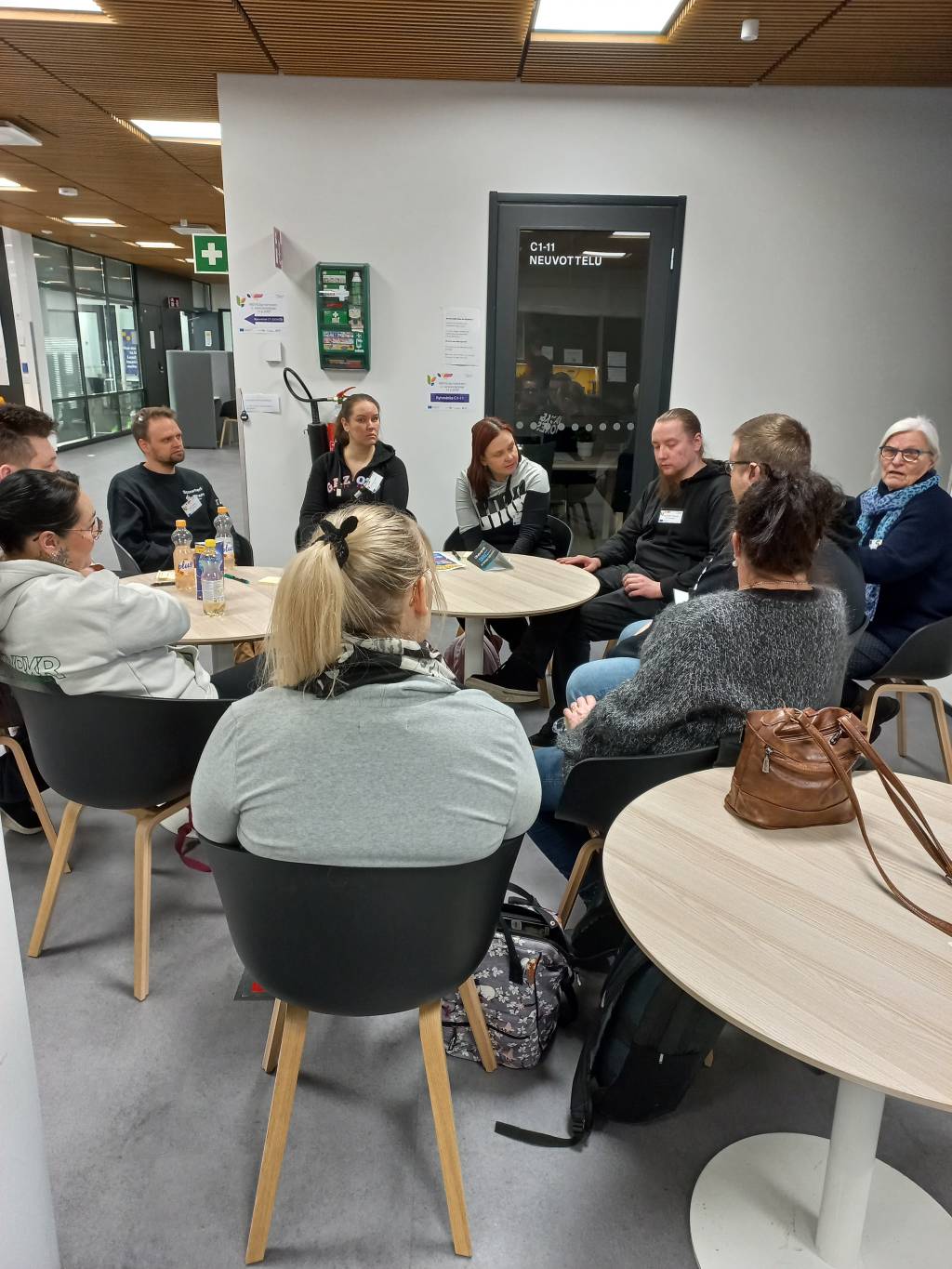 Ihmisiä istumassa pyöreiden pöytien ympärillä.