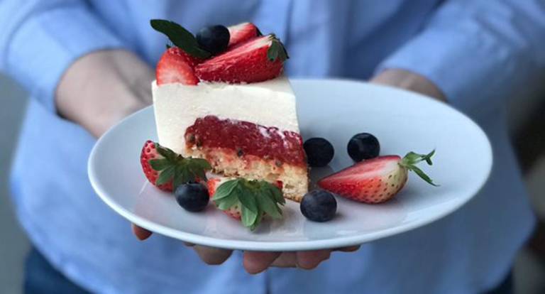 Marjoilla koristeltu kakkupala lautasella.