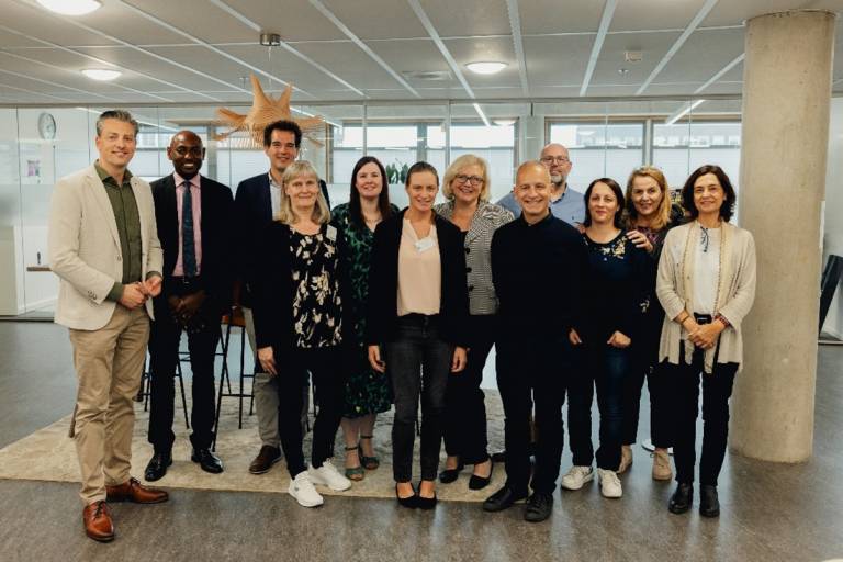 Ihmisiä seisomassa vierekkäin valoisalla käytävällä.