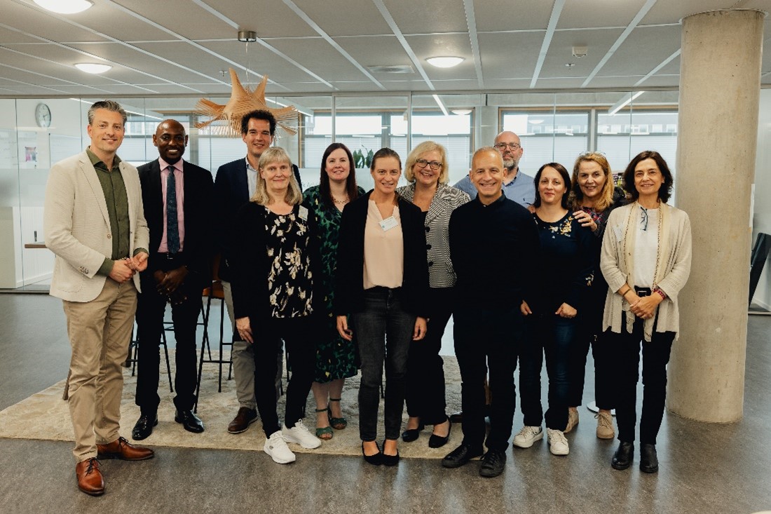 Ihmisiä seisomassa vierekkäin valoisalla käytävällä.