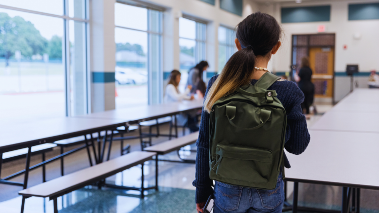 Tyttö luokkahuoneessa, jolla on reppu selässä.