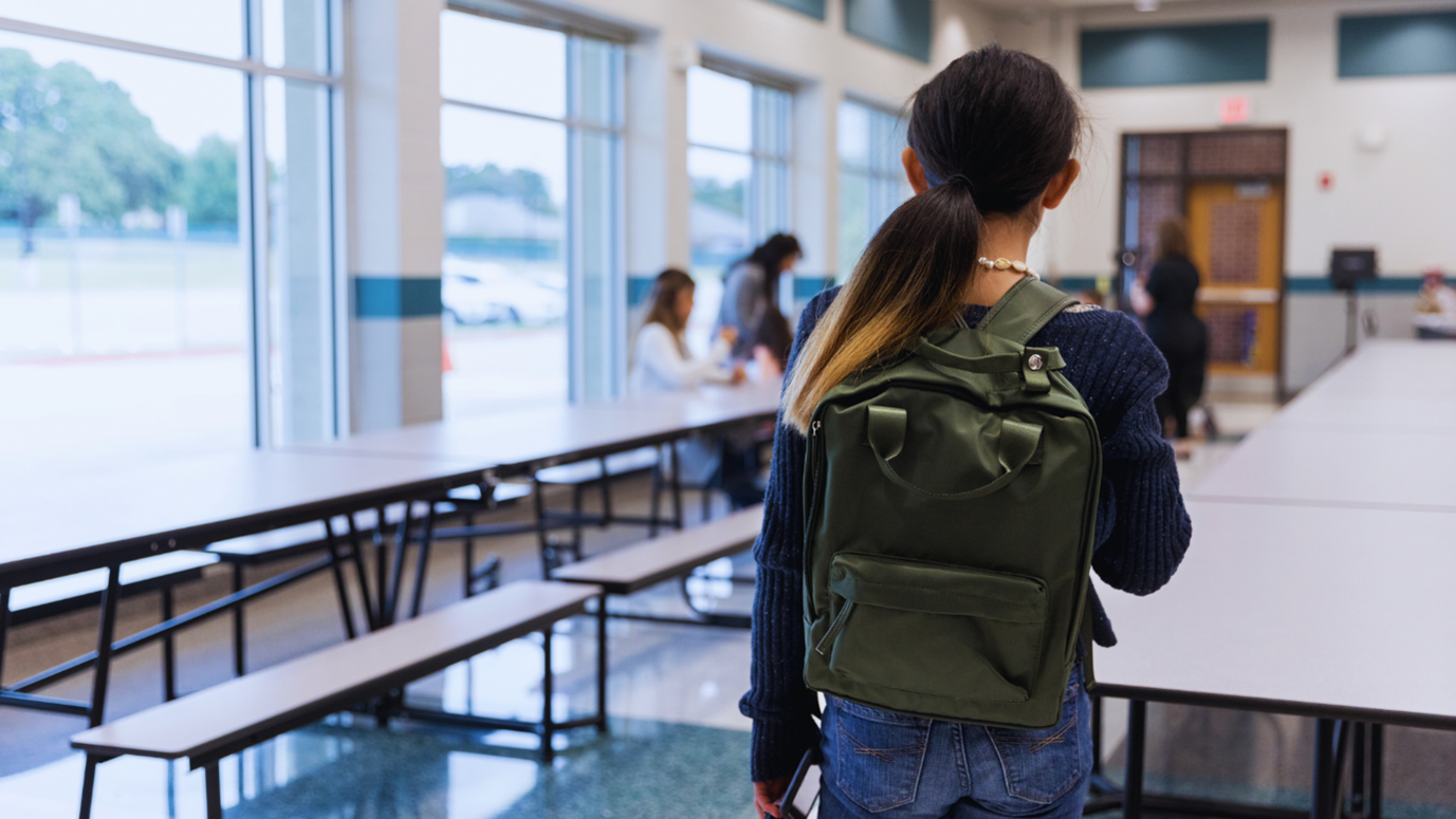 Tyttö luokkahuoneessa, jolla on reppu selässä.