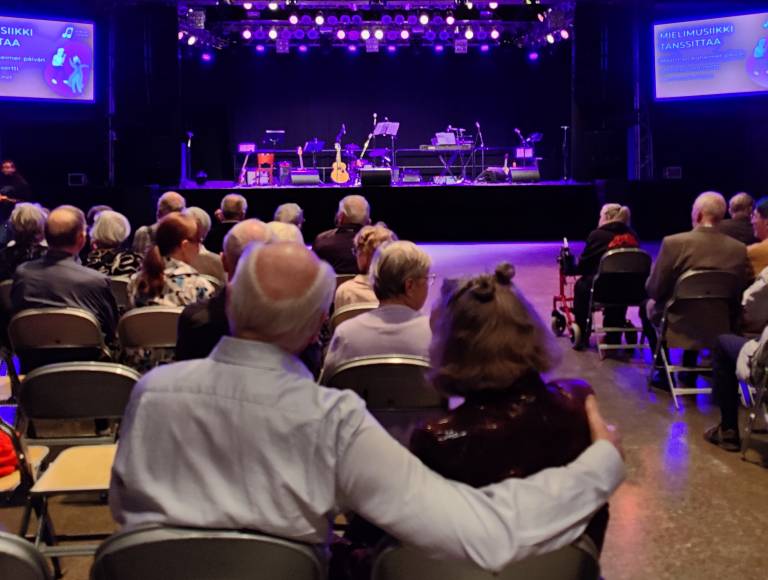 Elederly couple hugging each other and watching stage.