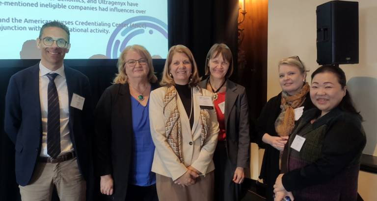 Kuusi henkilöä seisoo lavalla esityksen edessä.