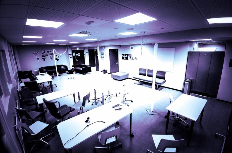 Kuva, jossa avoin luokkatila, istuimia ja työskentelypöytiä