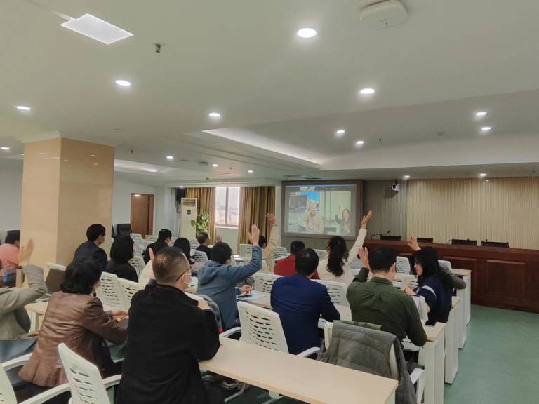 Students raising their hands in a classroom.
