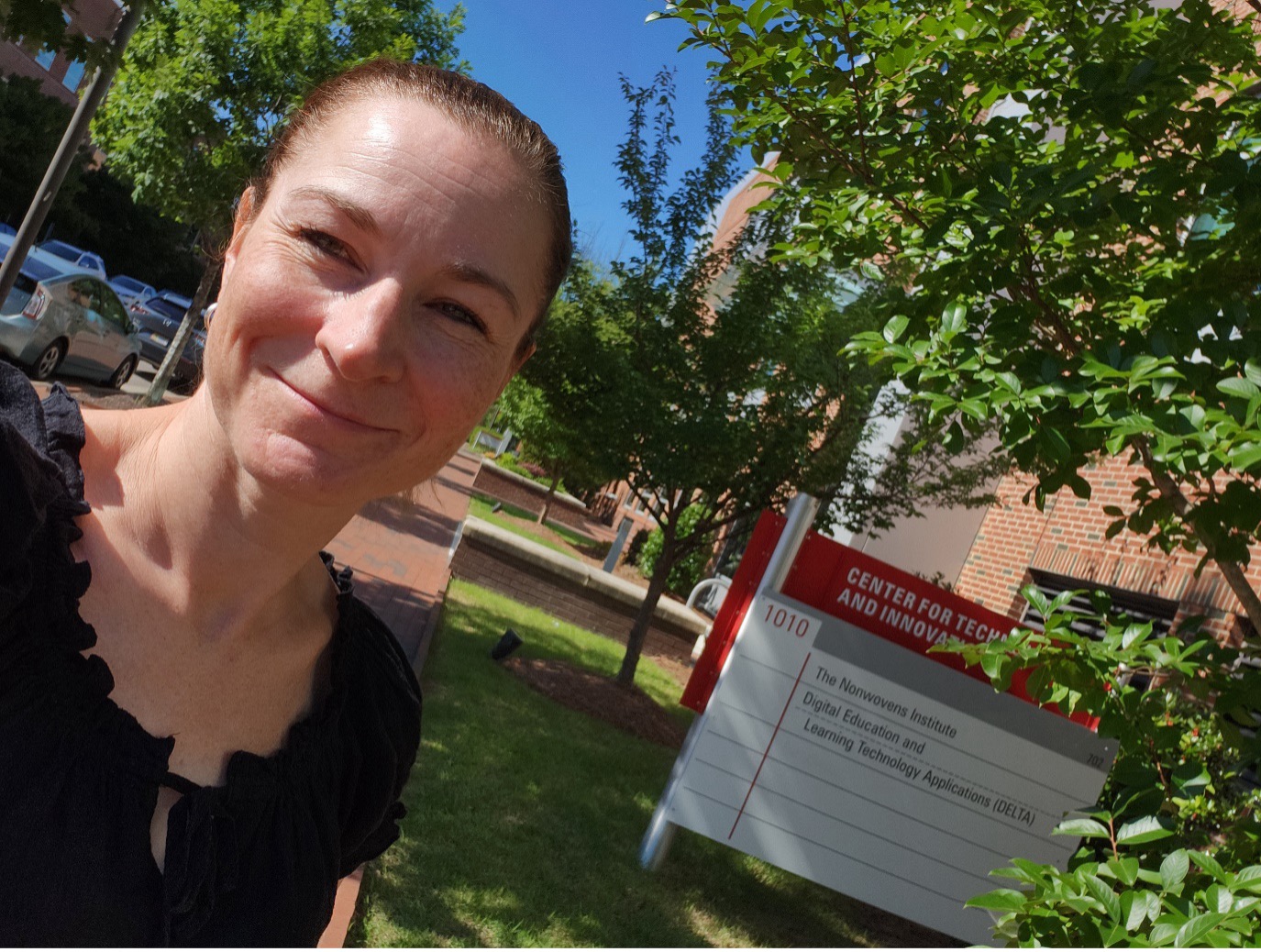 A woman smiling outside in sunshine.