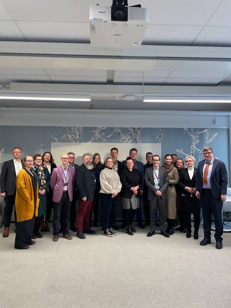 Ihmisiä seisomassa vierekkäin ryhmämuodostelmassa.