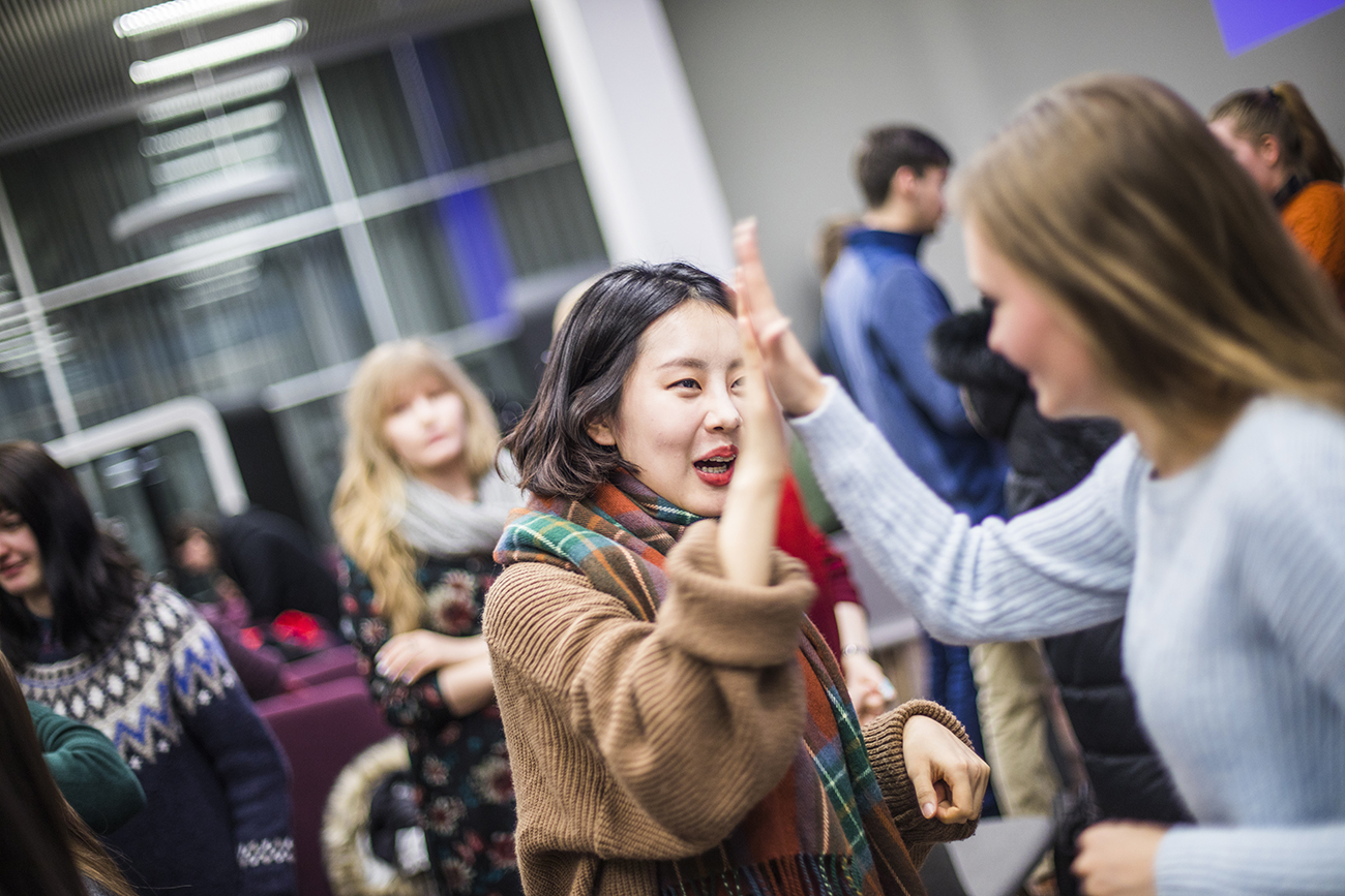 Kansainvälisten opiskelijoiden tilaisuus korkeakoulukampuksella, opiskelijoiden high five.