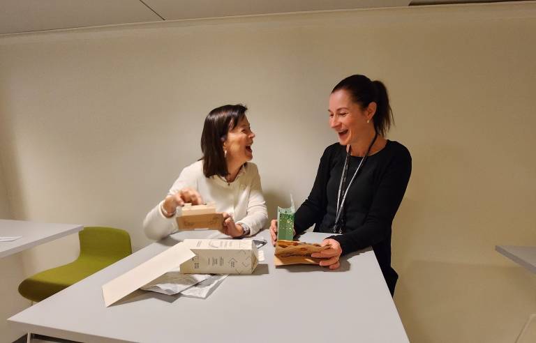 Kaksi ihmistä pöydän ääressä juttelemassa.