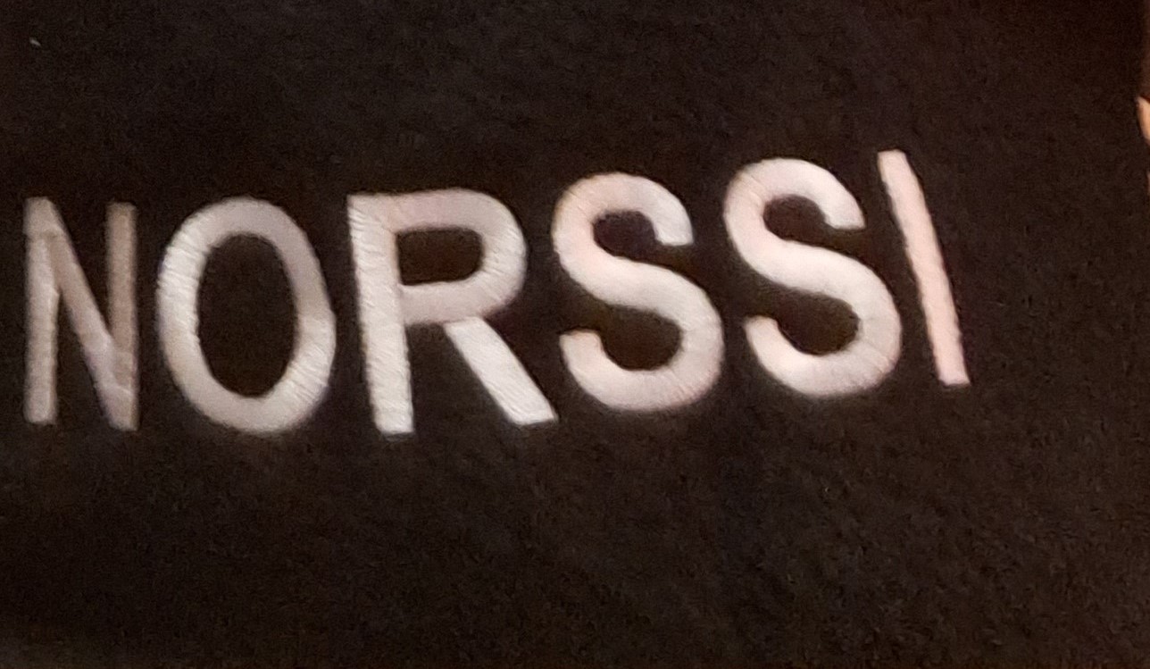 Kuva mustasta viltistä, jossa lukee valkoisella Norssi